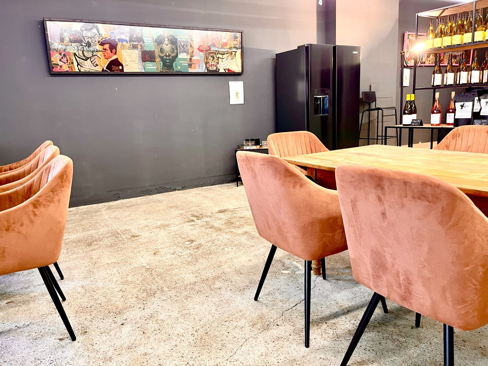 Sitzbereich im Kitchen Angel mit langem Holztisch, Samtstühlen und Weinregal
